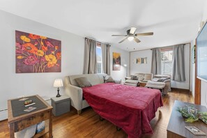 Une chambre moderne avec un lit, un canapé, une petite table et un ventilateur de plafond.