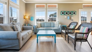 A living room with a sofa, armchair, coffee table, and a wall-mounted circular decoration. - Toes In The Sand 3 Bedroom Home (Port Bolivar)