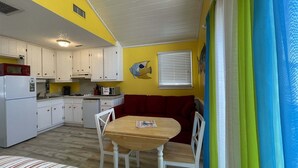 Eine kleine Küche mit weißen Schränken, einem roten Sofa und einem Holztisch.
