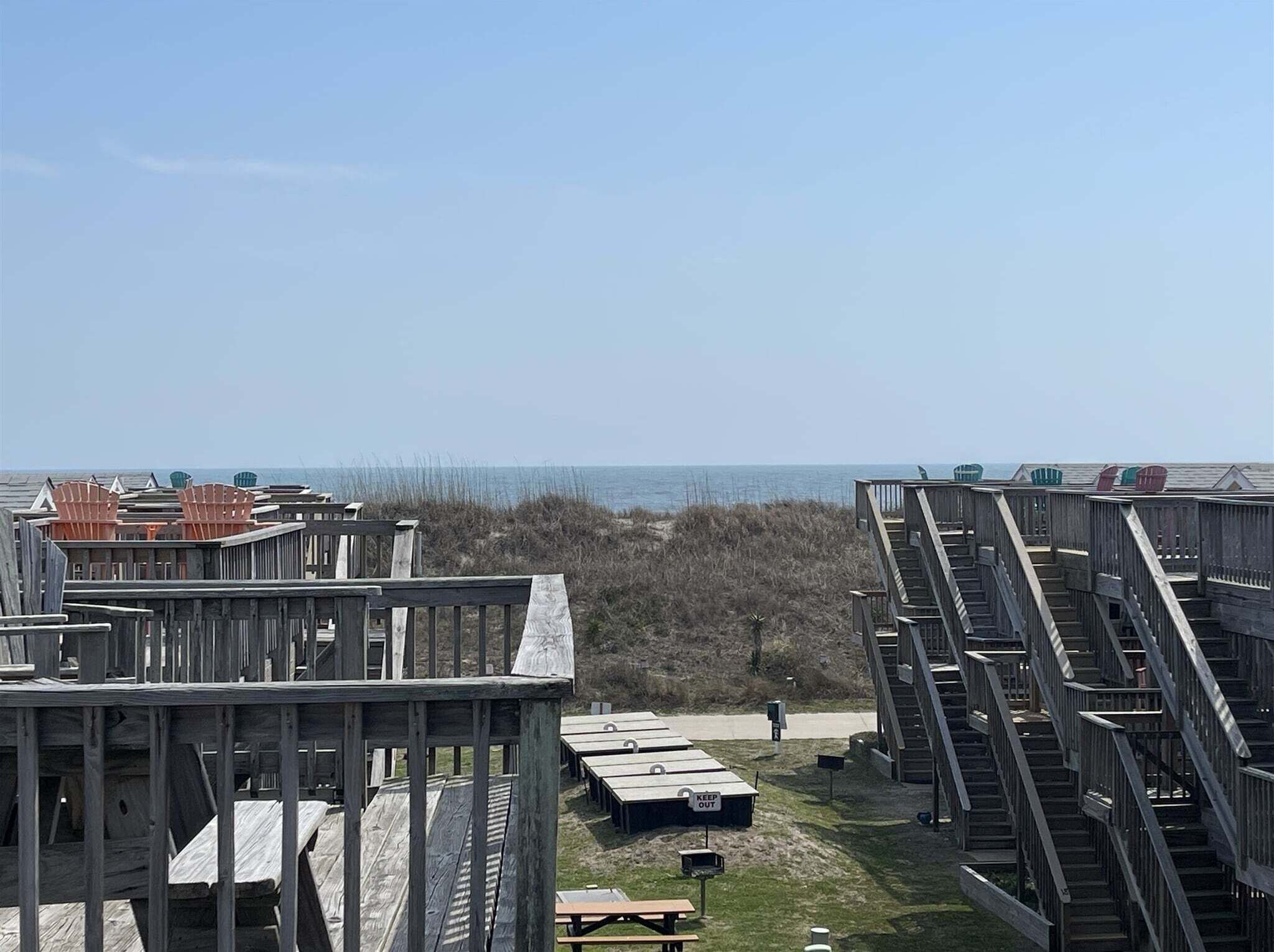 Una estructura de madera frente al mar, con varios niveles, una escalera y vistas al océano.