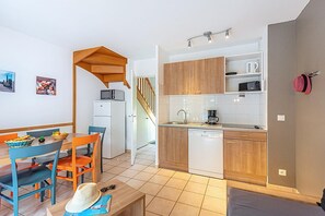 Une cuisine compacte dotée de meubles en bois, d’un lave-vaisselle et d’un coin repas avec une table et des chaises.