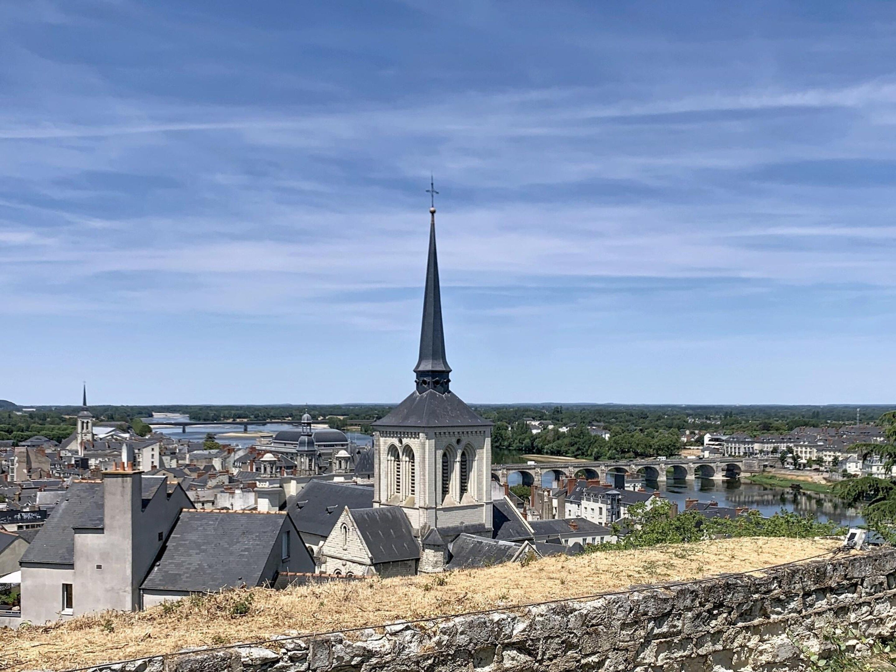 A church with a tall spire, surrounded by residential buildings and a river.