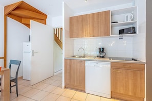 A compact kitchen with wooden cabinets, a dishwasher, and a microwave.