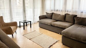 Una sala de estar con sofá, sillón, mesita y alfombra.