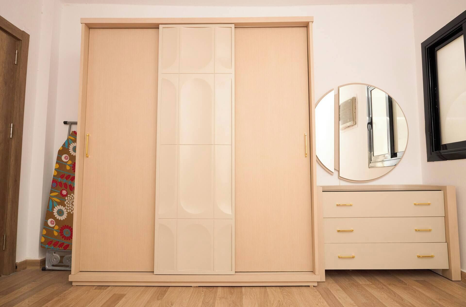 Une chambre équipée d’une armoire à portes coulissantes, d’un miroir, d’une commode avec des tiroirs et d’un radiateur.