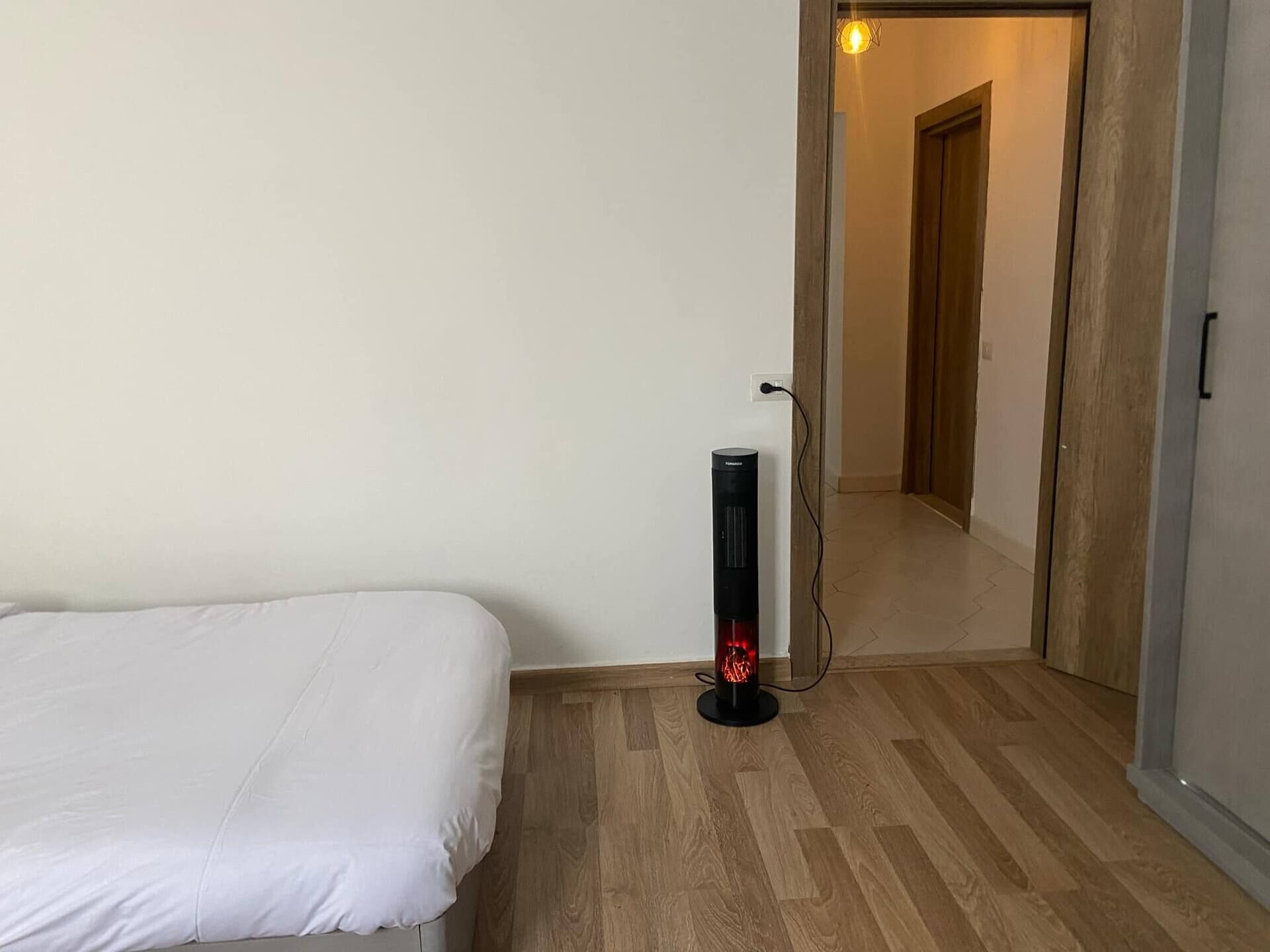 A bedroom with a bed, a heater, and a door leading to a hallway.