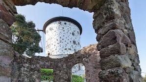 Eine alte Steinstruktur mit einem runden Turm, einer Steinsitzbank und einem schmalen Gang.