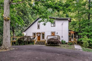 A white building with a porch, a front door, and a staircase leading to the entrance. - Dolly's Harmony Haven 3 Bedroom Cabin (Pigeon Forge)