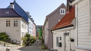 Eine schmale Kopfsteinpflasterstraße gesäumt von farbenfrohen Gebäuden, einem Briefkasten und einem kleinen Tisch mit Stühlen.