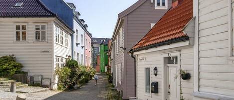 A narrow cobblestone street lined with colorful buildings, a mailbox, and a small table with chairs.
