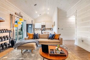 A spacious living room with a sofa, coffee table, and a view into the kitchen.