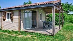 Un piccolo chalet in legno con patio, porte scorrevoli in vetro e un tavolo con sedie.