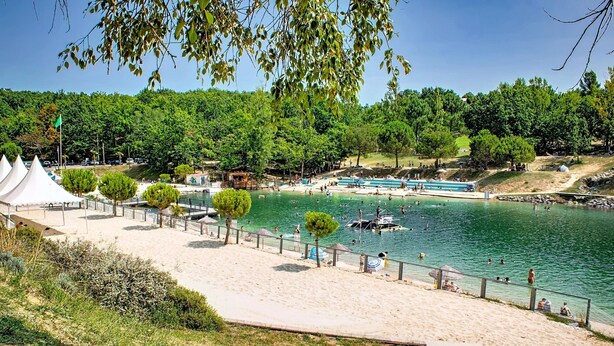 Una spiaggia con piscina, alberi e un'area sabbiosa.