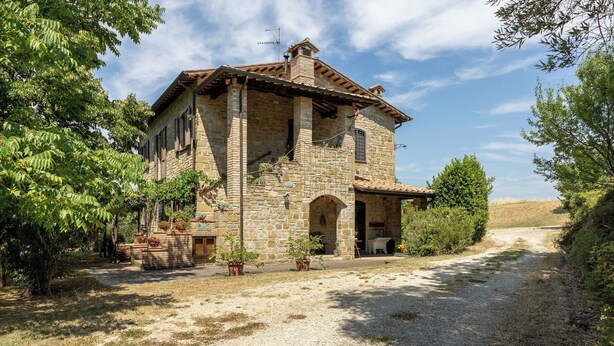 A stone building with a covered porch, a gravel driveway, and surrounding greenery. - Cosy apartment in villa with A/C, WIFI, pool, TV, patio, pets allowed and panoramic view (Perugia)