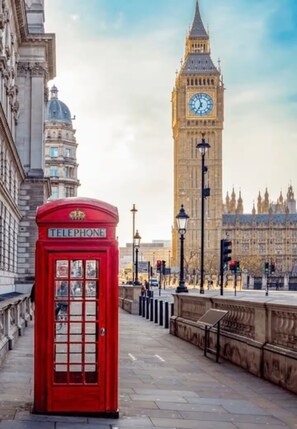 Eine rote Telefonzelle mit dem Big Ben im Hintergrund.
