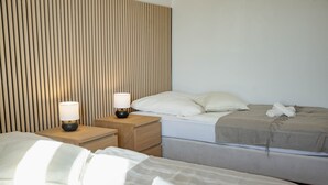 Ein Hotelzimmer mit zwei Betten, einem Lattenrost-Kopfende, Nachttischlampen und ordentlich bezogenen Betten mit Handtüchern.