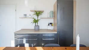 Eine moderne Küche mit Holzarbeitsplatte, einem eingebauten Kühlschrank und einer Topfpflanze.