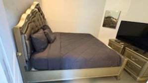 Une chambre à coucher avec un lit, une télévision et une commode.