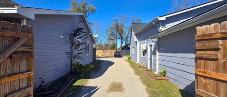 A narrow gravel path between two mobile homes with wooden fences on either side.