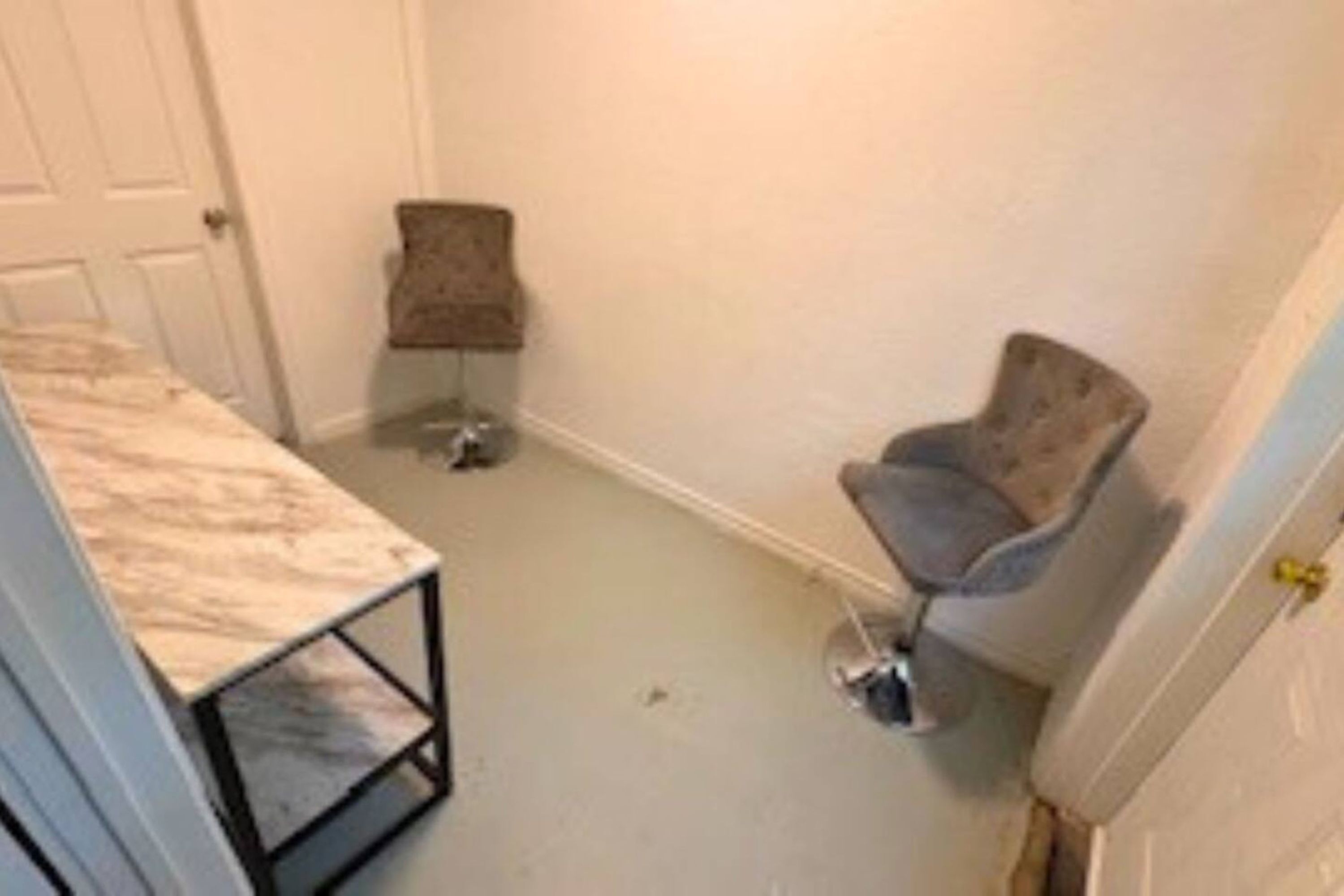 Une petite pièce avec un lit, une chaise et une porte.