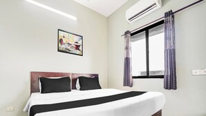 A hotel room with a bed, an air conditioner, a window with curtains, and a painting on the wall. - Hotel O Rajendra Nagar Hingna Road (Nagpur)