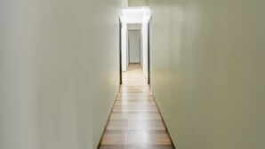 A narrow hallway with light-colored walls and wooden flooring, leading to a door at the end. - Hotel O Rajendra Nagar Hingna Road (Nagpur)