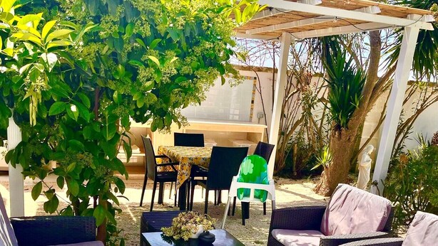 An outdoor patio with wicker furniture, a table, and a pergola.