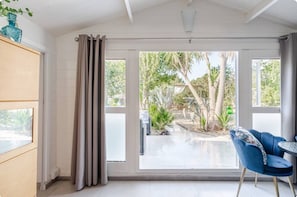 A room with a large sliding glass door leading to an outdoor area with plants and a pathway.