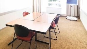 Een vergaderruimte met een tafel, stoelen, een whiteboard en een poster.