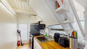 A compact kitchen with a wooden countertop, a sink, a stove, and a toaster.