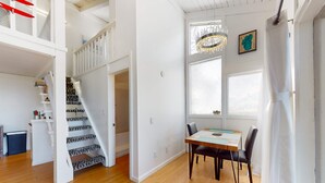 A spacious room with a staircase, a dining area with a table and chairs, and a chandelier.