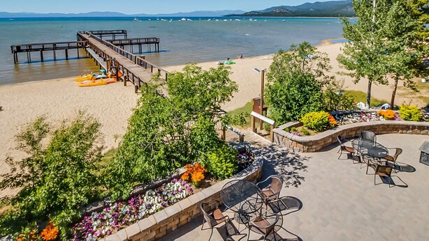 Une terrasse au bord de la plage, avec des sièges extérieurs, une terrasse en bois et une vue sur l’océan.