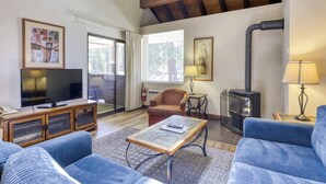 Ein gemütliches Wohnzimmer mit Fernseher, Sitzgelegenheiten, Kamin und großem Fenster.