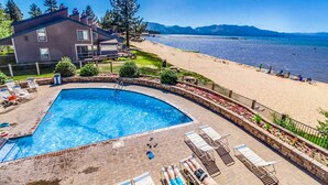 A swimming pool with lounge chairs, a beach, and a mountain view. - Cozy townhouse with pool access, deck, fireplace, and WiFi (South Lake Tahoe)