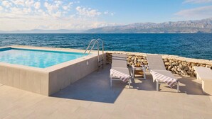 A swimming pool with a stone wall and lounge chairs. - Beachfront Stay With Private Pool (Supetar)