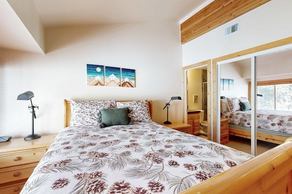 A bedroom with a bed, bedside tables, a mirror, and a painting on the wall. - Centrally located condo with pool, tennis, hot tubs, & fireplace - near skiing (Squaw Valley)