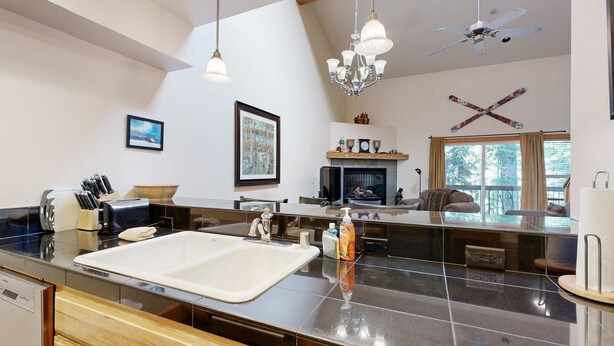 A modern kitchen with a large island, a fireplace, and a dining area with a view. - Centrally located condo with pool, tennis, hot tubs, & fireplace - near skiing (Squaw Valley)