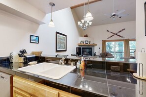 A modern kitchen with a large island, a fireplace, and a dining area with a view. - Centrally located condo with pool, tennis, hot tubs, & fireplace - near skiing (Squaw Valley)