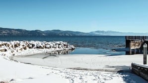 A snow-covered beach with a wooden pier and rocky shoreline. - A-frame home with large deck, game room, wood fireplace & near the lake - dogs ok (Carnelian Bay)