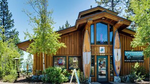 A wooden building with a large window, a sign for a beach cafe, and surfboards displayed outside. - A-frame home with large deck, game room, wood fireplace & near the lake - dogs ok (Carnelian Bay)
