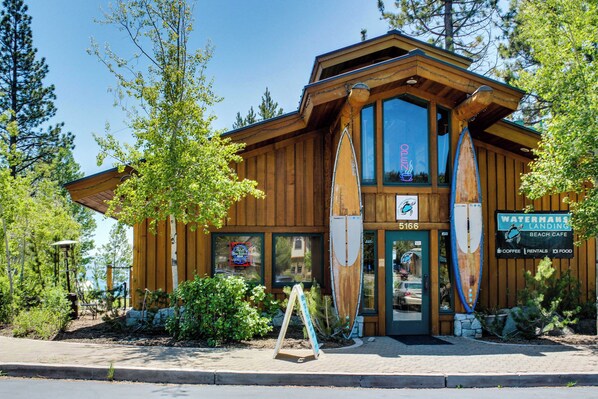 A wooden building with a large window, a sign for a beach cafe, and surfboards displayed outside. - A-frame home with large deck, game room, wood fireplace & near the lake - dogs ok (Carnelian Bay)