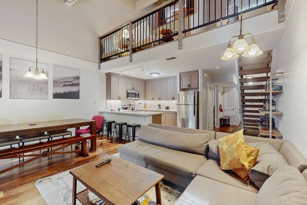 A spacious living area with a sofa, a dining table, and a kitchen in the background.