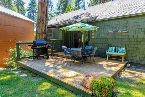 Una terraza con mobiliario exterior, una parrilla y un letrero que da la bienvenida a los visitantes al lago.
