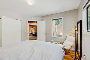 Ein Schlafzimmer mit Bett, Stuhl, Lampe und Fenster.