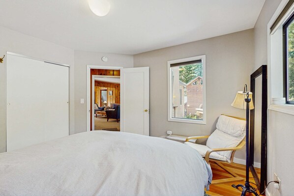 Ein Schlafzimmer mit Bett, Stuhl, Lampe und Fenster.