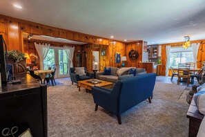 A cozy living room with a blue sofa, a coffee table, and a dining area with a table and chairs. - Welcoming home near the lake with furnished deck & large, enclosed yard (Tahoe Vista)