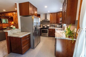 A modern kitchen with wooden cabinets, stainless steel appliances, and a marble countertop. - Welcoming home near the lake with furnished deck & large, enclosed yard (Tahoe Vista)