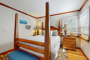 Ein Schlafzimmer mit einem hölzernen Himmelbett, einem Schminktisch und einem Fenster mit Jalousien.