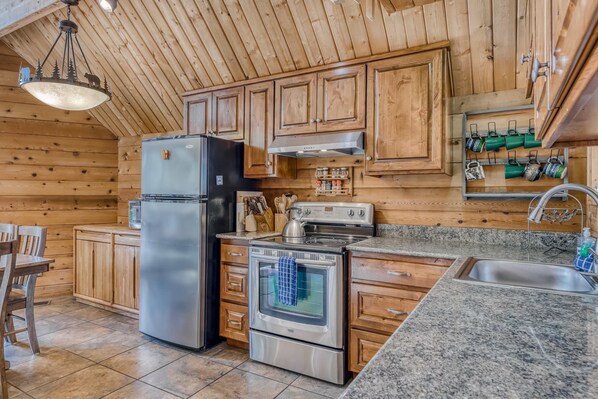 A kitchen with wooden cabinets, a stainless steel refrigerator, an oven, and a granite countertop. - Terrific Mountain Escape with Wood-Burning Fireplace, Easy Ski Access (Soda Springs)