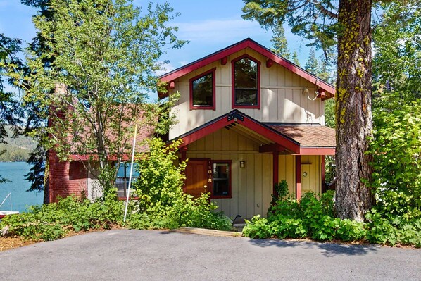 Et toetagers hus med rødt tag, en veranda og udsigt til en sø.